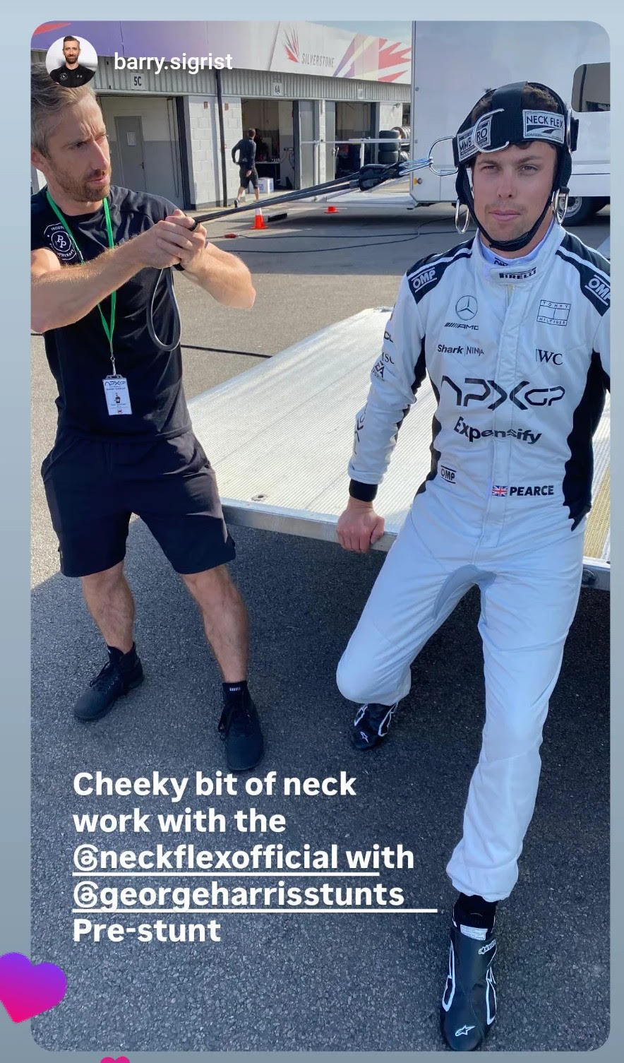 Trackside neck warm-up in a Neck Flex MMB Pro harness with band resistance applied by a trainer, driver in race suit beside the transporter