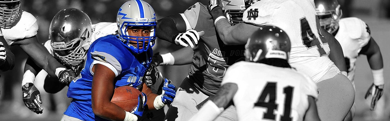 American football player in blue jersey running with ball, surrounded by teammates and opponents.