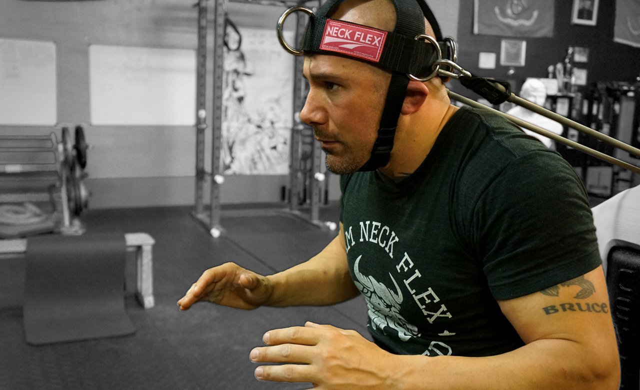 Man wearing a 'Neck Flex' headband in a gym setting